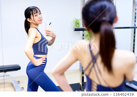 年輕女子在健身房用智慧型手機拍攝背部照片 私人健身房 肌肉訓練女孩 私人房間自拍 自拍 116402439