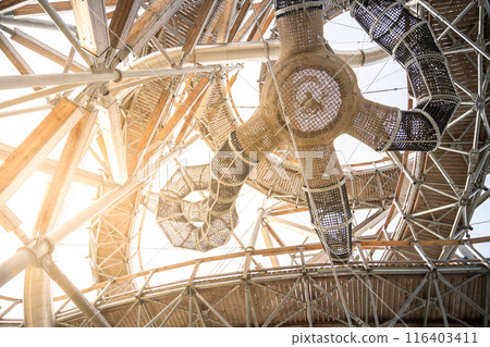 Looking up at a complex network of wooden beams and rope bridges inside the Sky Walk Tower, a popular attraction in Swieradow Zdroj, Poland. 116403411
