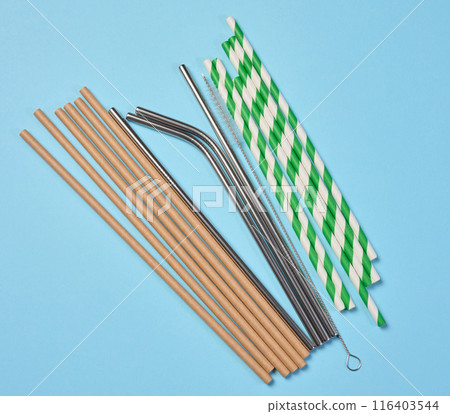 Disposable paper straws and metal cocktail straws on blue background, top view 116403544