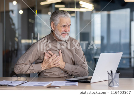 Elderly man suffering from chest pain while working at desk in modern office environment. Health crisis portrayed through distress and discomfort. Elderly man suffering from chest pain while working at desk in modern office environment. Health crisis portrayed through distress and discomfort. 116403567