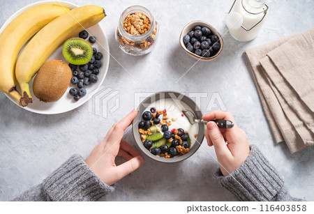 the child has breakfast with a hearty and healthy yogurt with granola and fresh fruits and berries the child has breakfast with a hearty and healthy yogurt with granola and fresh fruits and berries 116403858