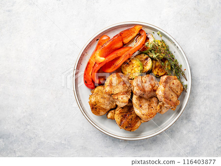 Grilled pork dish with fresh vegetables pepper and zucchini with spices in a plate  116403877