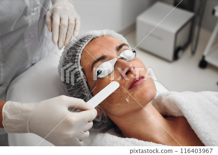 A woman applies gel to her face before a laser procedure. A woman applies gel to her face before a laser procedure. 116403967