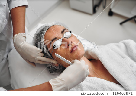 A woman applies gel to her face before a laser procedure. A woman applies gel to her face before a laser procedure. 116403971