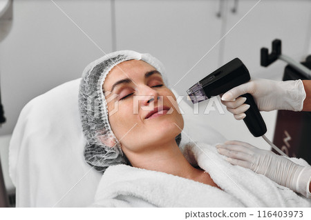 A woman receives Rf-lifting in a beauty salon. 116403973