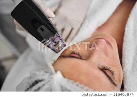 A woman receives Rf-lifting in a beauty salon. 116403974