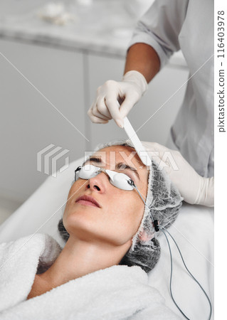 A woman applies gel to her face before a laser procedure. 116403978