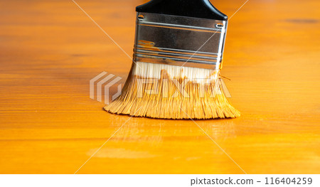 Painting table with brown enamel, brush in hand close-up, painting wood furniture process with brownish dye 116404259