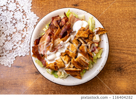 Polish Caesar salad with chicken, bacon and vegetables, high-calorie meat salad with fresh vegetables Polish Caesar salad with chicken, bacon and vegetables, high-calorie meat salad with fresh vegetables 116404282