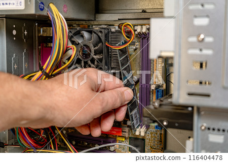 A technician installing a RAM bank into a computer. 116404478