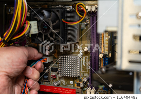 A technician disconnecting the power supply from a computer motherboard. 116404482