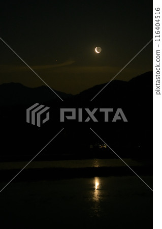 A thin moon with a lunar age of 26.4 is reflected on the surface of the water in a plowed rice field in Hakushu Town, Hokuto City. A thin moon with a lunar age of 26.4 is reflected on the surface of the water in a plowed rice field in Hakushu Town, Hokuto City. 116404516