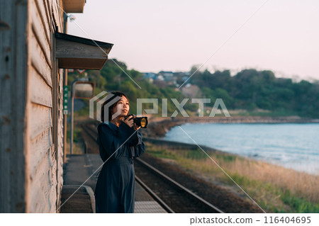 A woman holding a camera on the station platform 116404695