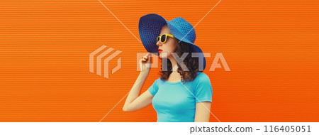 Summer portrait of beautiful stylish young woman posing in hat, glasses on bright orange background Summer portrait of beautiful stylish young woman posing in hat, glasses on bright orange background 116405051