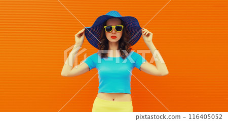 Summer portrait of beautiful stylish young woman posing in hat, glasses on bright orange background Summer portrait of beautiful stylish young woman posing in hat, glasses on bright orange background 116405052