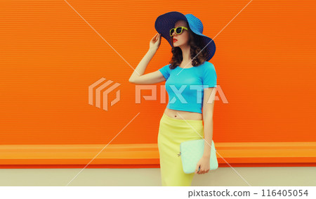 Summer portrait of beautiful stylish young woman posing in hat, glasses on bright orange background 116405054