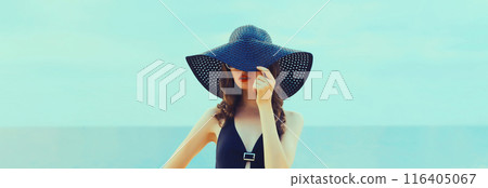 Summer beautiful young woman in bikini swimsuit, black hat, stylish girl posing on the beach on sea 116405067