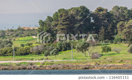 Modern golf courses for tourists with clear ponds and palm trees for relaxation and golf timelapse. Lagos, Portugal, Algarve. 116405151