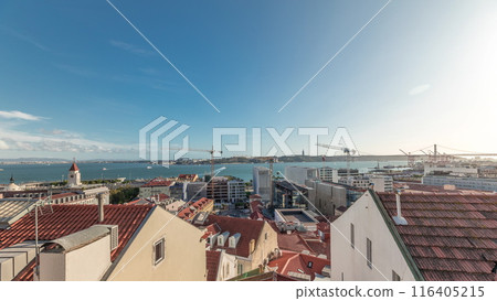 Panorama showing red roofs timelapse and 25 de Abril Bridge, Iconic suspension bridge over Tagus River in Lisbon, Portugal. 116405215