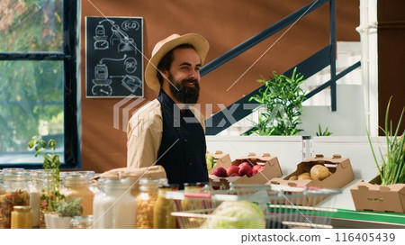 Happy man spraying fresh produce to preserve aroma and smell, zero waste supermarket vendor. Owner with hat and apron taking care of fruits and vegetables placed for sale, neighborhood shop. Happy man spraying fresh produce to preserve aroma and smell, zero waste supermarket vendor. Owner with hat and apron taking care of fruits and vegetables placed for sale, neighborhood shop. 116405439