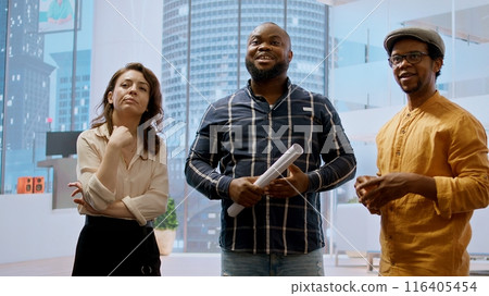 Real estate broker and client analyzing blueprints for an office space, evaluating the property and reaching a contract agreement. Businessman planning an investment strategy. Camera A. Real estate broker and client analyzing blueprints for an office space, evaluating the property and reaching a contract agreement. Businessman planning an investment strategy. Camera A. 116405454