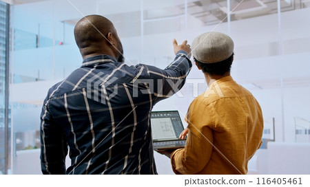 Real estate team and businesswoman discussing workspace design and planning, reviewing layout blueprints during an office tour. Investing in property leasing for startup development. Camera A. 116405461