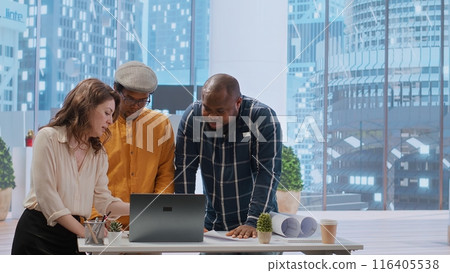 Business professionals and a real estate agent engage in a planning session, discussing the layout and design of a new office space based on detailed blueprints. Property investment. Camera B. Business professionals and a real estate agent engage in a planning session, discussing the layout and design of a new office space based on detailed blueprints. Property investment. Camera B. 116405538