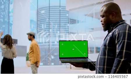 Realtors and client evaluating blueprints next to green screen display, working on new high class office space layout development. Businesswoman sharing her interior design vision. Camera A. Realtors and client evaluating blueprints next to green screen display, working on new high class office space layout development. Businesswoman sharing her interior design vision. Camera A. 116405567