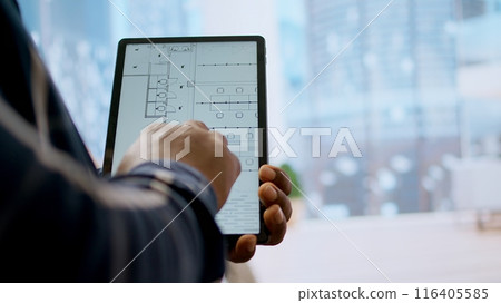Financier realtor and client examining blueprints on a tablet and establishing the renovation plans before reaching an agreement. Businessman planning an investment during office tour. Camera A. Financier realtor and client examining blueprints on a tablet and establishing the renovation plans before reaching an agreement. Businessman planning an investment during office tour. Camera A. 116405585