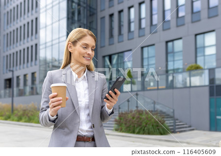 Confident businesswoman standing outside modern office building using smartphone and holding coffee cup. Professional attire and urban setting suggest productive and efficient workday Confident businesswoman standing outside modern office building using smartphone and holding coffee cup. Professional attire and urban setting suggest productive and efficient workday 116405609