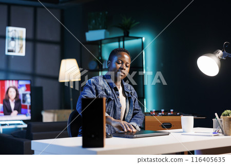 African american female freelancer opening personal computer, getting ready to work at her home office desk. Determined black woman about to use digital laptop for online research. 116405635