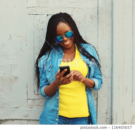 Happy young woman with phone, modern smiling girl looking at smartphone in casual in the city 116405657