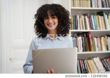 Beautiful smart girl using laptop studying for class assignment in university library 116406388