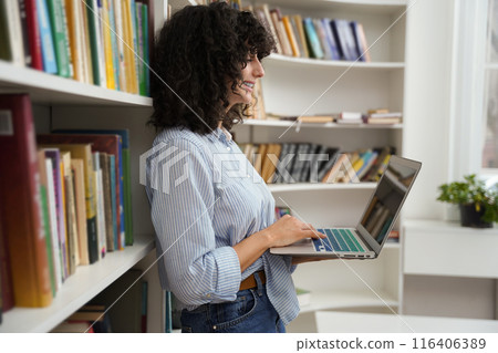 Beautiful smart girl using laptop studying for class assignment in university library 116406389