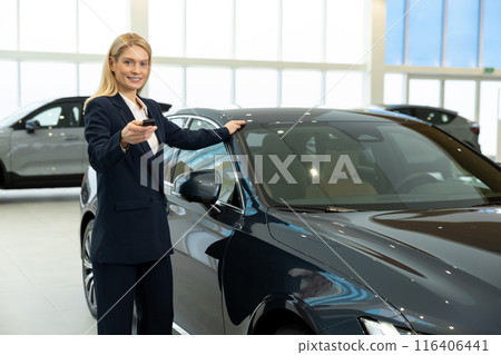 Blonde woman in elegant suit standing near the car with the key Blonde woman in elegant suit standing near the car with the key 116406441