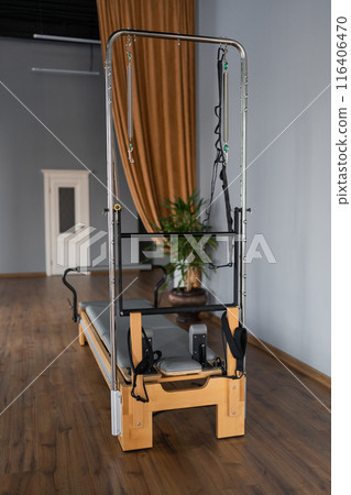 Pilates equipment. Reformer bed. Reformer pilates studio machine for fitness workouts in gym. Fit, healthy and strong authentical body. Fitness concept Pilates equipment. Reformer bed. Reformer pilates studio machine for fitness workouts in gym. Fit, healthy and strong authentical body. Fitness concept 116406470