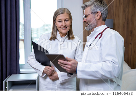 Doctors having a changeover in a clinic and sharing information Doctors having a changeover in a clinic and sharing information 116406488