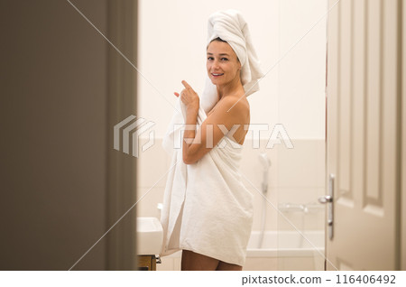 Slim young woman in white towel standing in the bathroom Slim young woman in white towel standing in the bathroom 116406492
