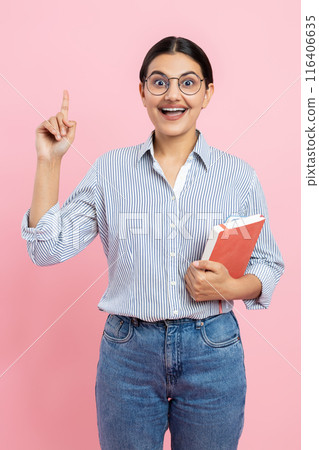 Inspired girl in casual shirt holding organizer pointing finger up having idea 116406635