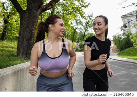 Plus-size woman losing weight while running with her trainer in stadium outdoors Plus-size woman losing weight while running with her trainer in stadium outdoors 116406846