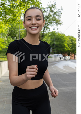 Woman running on asphalt road in summer park active sporty female Woman running on asphalt road in summer park active sporty female 116406847