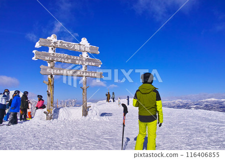 Rusutsu ski resort in Hokkaido, Japan on a clear winter day, Isola summit sign in the East area, Mt. Yotei with skiers and snowboarders 116406855