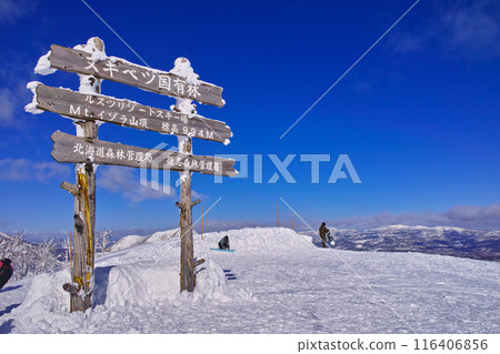 Snowboarders with Mt. Yotei and Isola summit sign in the East Area of Rusutsu Ski Resort in Hokkaido, Japan on a clear winter day 116406856