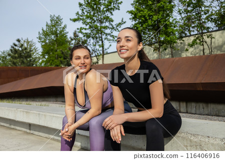 Women sitting on stairs on stadium while having break during outdoor loosing weight workout Women sitting on stairs on stadium while having break during outdoor loosing weight workout 116406916
