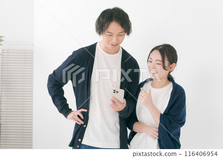 Smiling men and women looking at smartphones 116406954