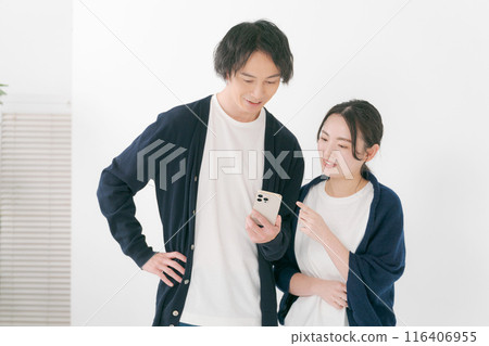 Smiling men and women looking at smartphones 116406955