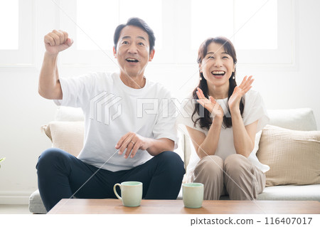 A couple doing a fist pump while watching sports or fun TV 116407017