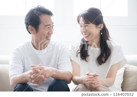 一對 50 多歲的中年夫婦在漂亮的背光客廳裡交談時凝視對方的特寫 116407032