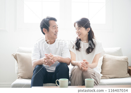 一對 50 多歲的中年夫婦在美麗的背光客廳裡聊天，廣角地看著對方 116407034