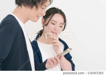 Smiling men and women looking at smartphones 116407265